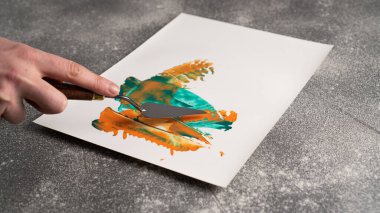 Standart palet bıçağını tutarak ve beyaz kağıda soyutlama resmi yaparak. Palet bıçağını bırak