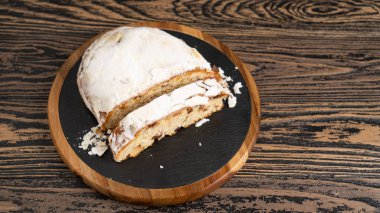 Tahta masada bir dilim Stollen. Siyah kesme tahtası kremalı ev yapımı Stollen. Fındık ve baharatlı meyveli ekmek.