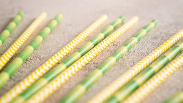 Bamboo straws. Yellow and green paper straws. Colored cocktail tubes. Striped drink straws of different colors