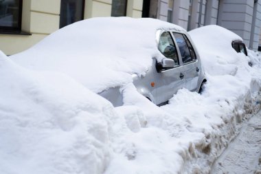 Araba sokakta karın altında kalmış. Kışın caddelerde karla kaplı arabalar. Kar fırtınası üstüne şehir caddesi
