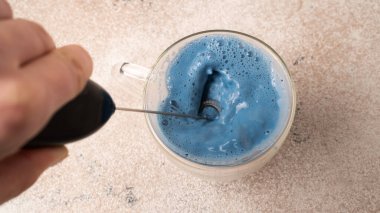 Kibrit mavi çay pişirme işlemi. Mavi matcha latte 'yi yenmek için el çırpıcı. Çayı çırpıyorum.