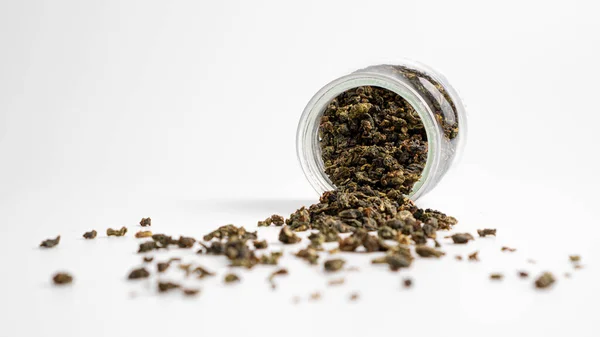 Süt yaprakları beyaz arka plana saçılmış. Küçük cam bir kavanozda Çin sütlü oolong çayı. Mayalanmış çay.