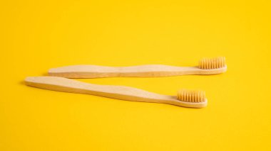 Ahşap diş fırçaları sarı arka planda yatar. Ekolojik bambu diş fırçaları