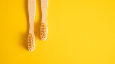 Sarı arka planda solda iki bambu diş fırçası. Tahta diş fırçaları ile eko konsepti