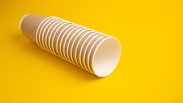 Montón de taza de papel desechable aislado sobre fondo amarillo. Tazas de papel de café. Concepto de comida para llevar y para llevar — Foto de Stock