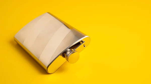 Metal pocket bottle. Stainless hip flask isolated on a yellow background. Steel flask. Steel bootle. Aluminum hip flask