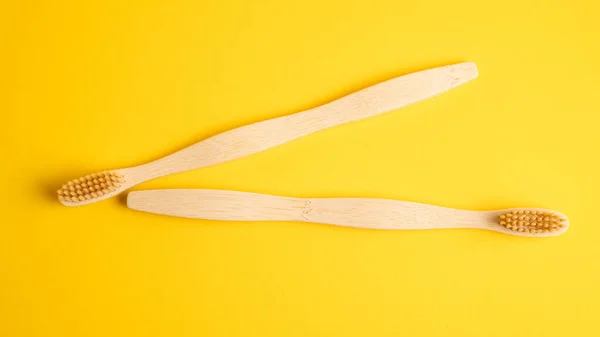 Wooden toothbrushes lie on a yellow background. Ecological bamboo toothbrushes. Top view — Stock Photo, Image