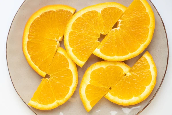 Naranjas perfectamente cortadas en rodajas en un plato gris. Mitad de anillos de naranjas en el plato. Las naranjas saturadas se cortan en un plato — Foto de Stock