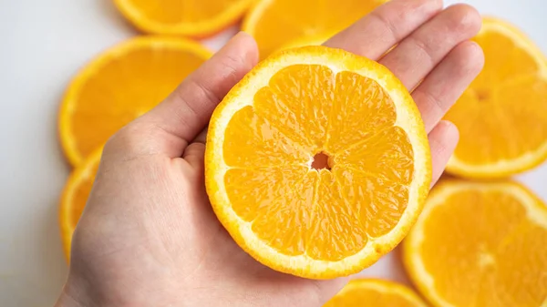 Círculo laranja perfeito na palma da mão. Mão segura uma fatia de laranja suculenta — Fotografia de Stock