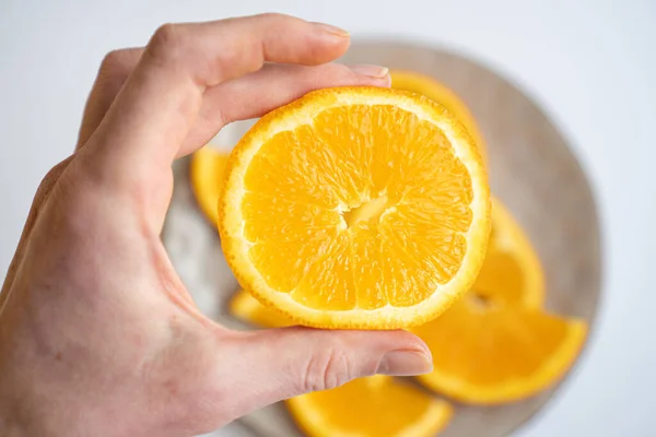 Fatia de citrinos na mão. Mão apertando uma fatia de laranja. Vitaminas de inverno, laranja suculenta perto — Fotografia de Stock