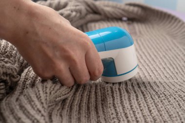 Örgü süveter arka planında elektronik tıraş makinesi. Tiftik temizleme makinesi. Kumaş traş aracı