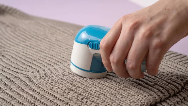 Örgü süveter arka planında mavi elbiseler traş edici. Tiftik temizleme makinesi. Kumaş traş aygıtı