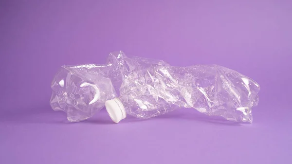 Conceptul de poluare cu plastic pe fundal violet. Sticlă zdrobită pe fundal violet. Sticlă transparentă din plastic — Fotografie, imagine de stoc