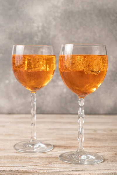 Ev yapımı Aperol spreyi. Ahşap masada turuncu kokteyller. Basit Aperol Spritz Tarifi. Bardakta buzlu Aperol spreyi.
