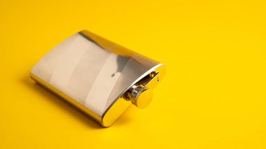 Sarı arka planda metal matara. Alkol izole edilmiş kalça matarası. Paslanmaz içki şişesi izole edilmiş.