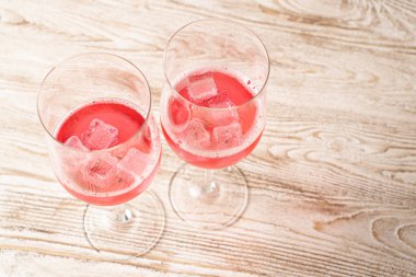 İki bardak gül kokteyli. Evdeki ahşap masada buzlu, köpüklü kırmızı kokteyl. Ev yapımı kırmızı kokteyller.