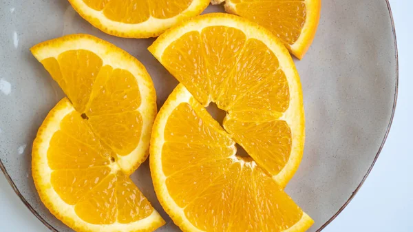Idealnie pokrojone pomarańcze na szarym talerzu. Pół pierścienia pomarańczy na talerzu. Pomarańcze nasycone są krojone na talerzu — Zdjęcie stockowe