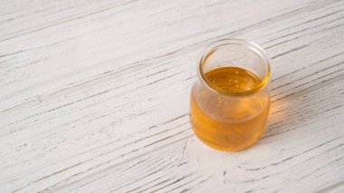 Beyaz ahşap bir masada, basit bir kavanozdaki bal porsiyonu. Açık bal kavanozunun ayrıntıları. Cam bir kavanozda bal kabarcıkları