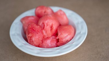 Karpuz topları. Beyaz kasede kırmızı toplar. Sulu olgun karpuz. Ev karpuzu porsiyonu