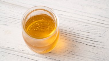 Beyaz ahşap bir masada, basit bir kavanozdaki bal porsiyonu. Açık bal kavanozunun ayrıntıları. Cam bir kavanozda bal kabarcıkları