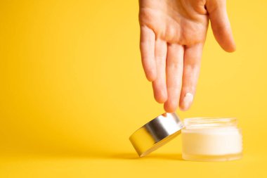 Sarı üzerine el kremi. El nemlendirici sürüyorum. Beyaz kremalı parmak. Güzellik arka planı