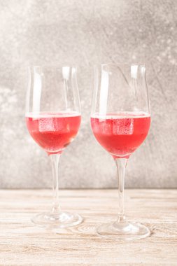 İki bardak gül kokteyli. Evdeki ahşap masada buzlu, köpüklü kırmızı kokteyl. Ev yapımı kırmızı kokteyller.