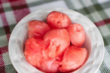 Karpuz topları. Beyaz kasede kırmızı toplar. Sulu olgun karpuz. Doğal bir kasede karpuz topları