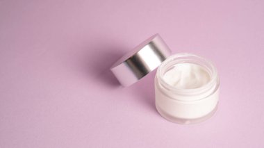 Beyaz nemlendirici fotoğraf. Nemlendiriciyi mor arka planda kavanoza koy. Şeffaf kabın içindeki krema