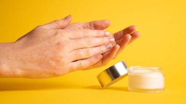Sarı üzerine el kremi. Kadın ellerine el nemlendirici kremi sürüyorum.