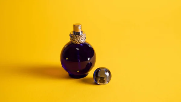 Liten blå parfymburk på gult. Flaska med essentiell parfym. Blå glassprayflaska för kunglig doft. Köln — Stockfoto