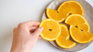 Büyük portakal dilimleri yakın mesafede. Beyaz arka planda turuncu daireler. El soyma portakal dilimleri
