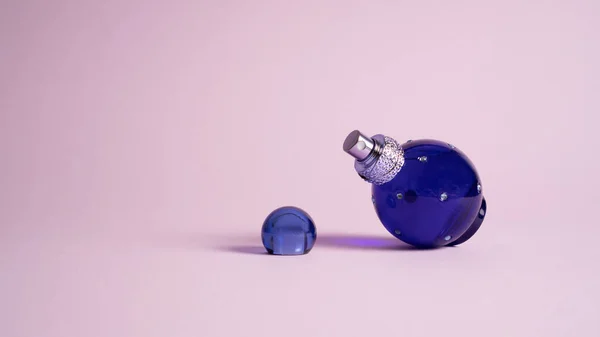 Kleine blauwe parfumflesje op violet. Keulen pot op paars. Mini flesje parfum Rechtenvrije Stockafbeeldingen