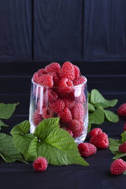 Koyu ahşap arka planda taze, kırmızı ahududular. Yeşil yapraklar. Metin için yer