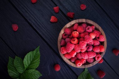 Koyu ahşap arka planda taze, kırmızı ahududular. Yeşil yapraklar. Metin için yer