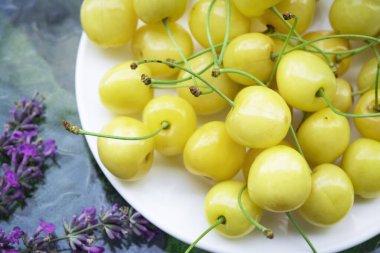 Sarı kirazlar beyaz bir tabakta yakın plan. Güzel bahar Nefis arka plan