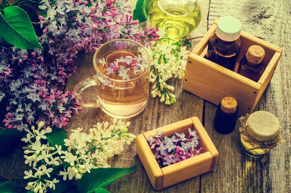 Flaschen Mit Natürlichem Ätherischem Und Eine Tasse Tee Aus Fliederblüten — Stockfoto