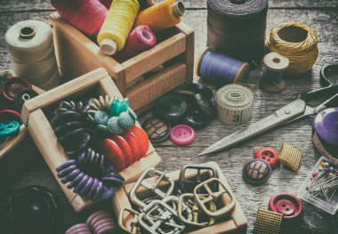 Dikiş seti. Eski dikiş malzemeleri ve el dikiş aletleri. Dikiş, iplik, makas, iğne ve eski ahşap bir yüzeye terzi tezgahı dikmek için aksesuarlar. Retro tonin