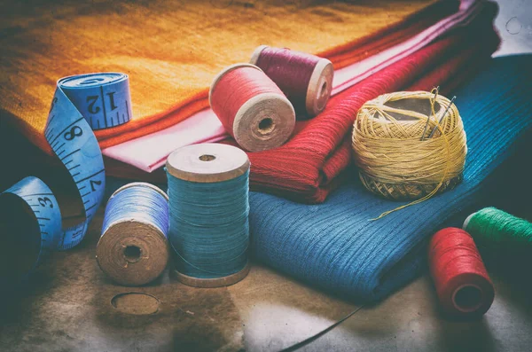 Dikiş işi için çeşitli aksesuarlar. Dikiş için dikiş iplikleri, iplik makaraları, kumaşlar, santimetre yakın çekim. Yaratıcı bir imaj. Retro biçimi 