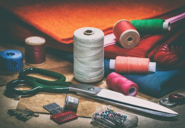 Yaratıcı bir imaj. Dikiş için iplik dikmek ve dikiş işi için çeşitli aksesuarlar. Dikiş için bir takım aksesuarlar, iplik makaraları, kumaşlar, makas ve yüksük gibi yakın çekim. Retro biçimi 