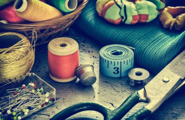 Retro dikiş malzemeleri. Dikiş işi için çeşitli aksesuarlar. Dikiş için bir takım aksesuarlar, iplik makaraları, kumaşlar, makas ve yüksük gibi yakın çekim. Retro styl