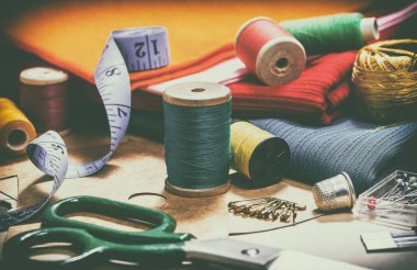 Yaratıcı bir imaj. Dikiş için iplik dikmek ve dikiş işi için çeşitli aksesuarlar. Dikiş için bir takım aksesuarlar, iplik makaraları, kumaşlar, makas ve yüksük gibi yakın çekim. Retro biçimi 