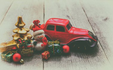 Noel hediyesi, kırmızı minyatür araba, kardan adam ve tahta yüzeyde hediyeler. Noel tatili kavramı. Kart. Metin için boş alan, retro styl