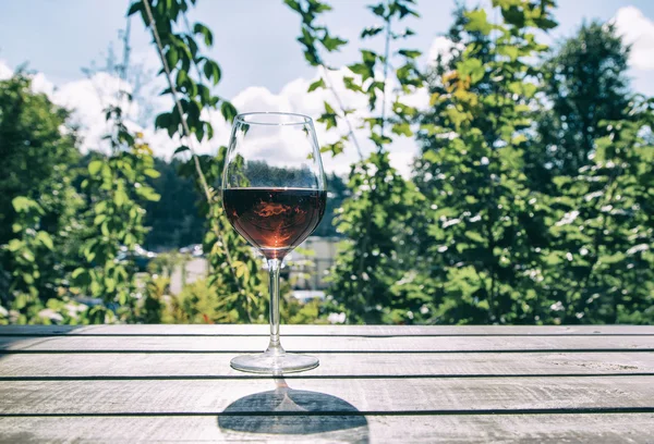Glass of red wine on a background of green plants — Stock Photo, Image