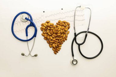 Mavi ve koyu steteskop, badem ve elektrokardiyogramdan yapılmış bir kalp.