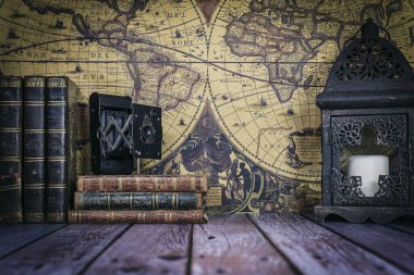 Klasik bir haritanın arka planında antik kitaplar, kamera ve saatten oluşan natürmort bir hayat..