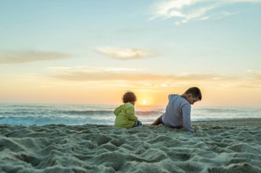 Günbatımında Portekiz 'in kuzey sahilinde batan güneşi gösteren iki beyaz çocuk..