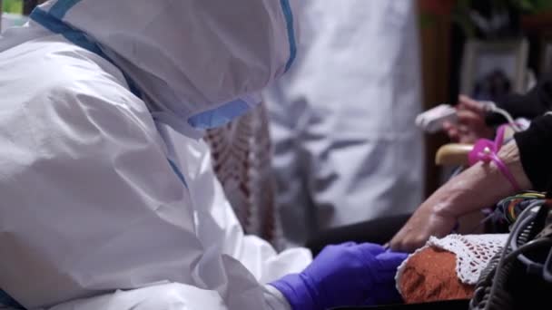 救急看護師や個人の保護具を身に着けている救急救命具のパイプ ニトリル手袋 フェイスマスクは コロナウイルスCovid 19パンデミックの間に血を引くために針で患者の手を刺す — ストック動画