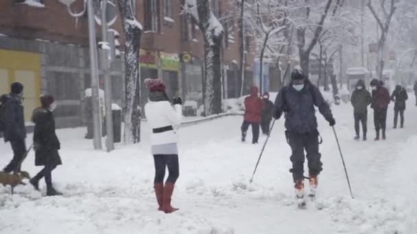 西班牙菲洛米娜风暴袭击马德里 成为1971年以来最大的降雪场 当其他行人在被雪覆盖的街道上行走时 一名男子在马德里市中心的马路中间练习滑雪 — 图库视频影像