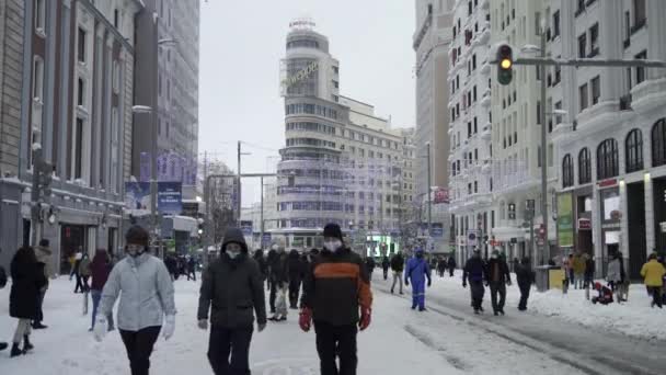 Tuziny Ludzi Spacerują Środku Gran Madrycie Przykryte Śniegiem Kultowym Budynkiem — Wideo stockowe