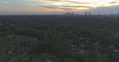 Atlanta Havalimanı v565 Panoramik şehir manzarası gün batımında gökdelen gökdelenleri ve ağaçlarla altın parkurun üzerinde uçuyor - Ekim 2019